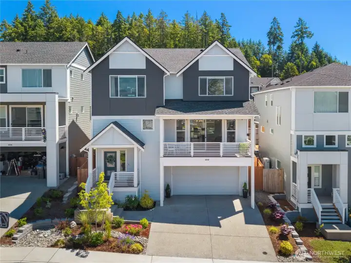 Modern multi-level front exterior features a two-car garage, improved front door lock, and custom mature landscaping with decorative river rock accents, ornamental trees, and perennial garden beds. Modern multi-level front exterior features a two-car garage, improved front door lock, and custom mature landscaping with decorative river rock accents, ornamental trees, and perennial garden beds.