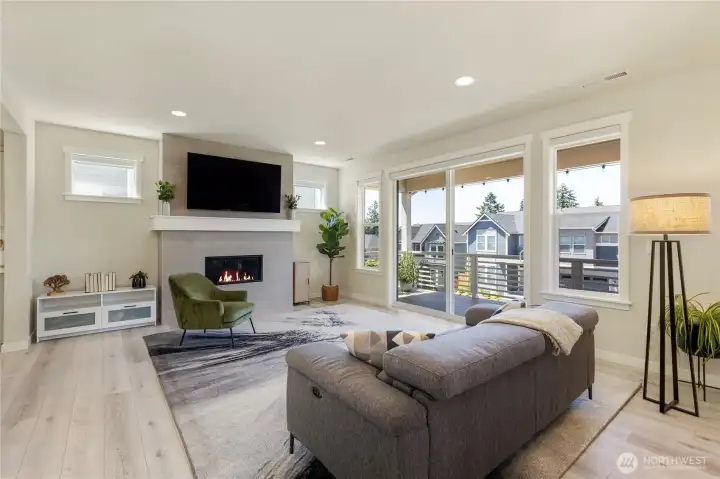Open great room features wide-plank flooring, a tile-surround gas fireplace, custom motorized blinds, and a custom wall TV mount that conveys with the property. Open great room features wide-plank flooring, a tile-surround gas fireplace, custom motorized blinds, and a custom wall TV mount that conveys with the property.