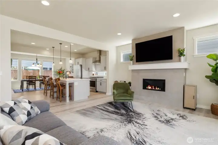 Spacious main living area features wide-plank luxury vinyl flooring, a modern gas fireplace with tile surround, and large windows with custom motorized blinds. Spacious main living area features wide-plank luxury vinyl flooring, a modern gas fireplace with tile surround, and large windows with custom motorized blinds.