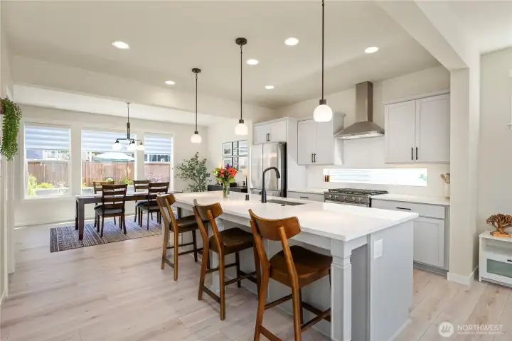 Chef's kitchen features premium stainless steel appliances, slab countertops, transitional shaker cabinetry, recessed lighting, and wide-plank luxury vinyl plank flooring. Chef's kitchen features premium stainless steel appliances, slab countertops, transitional shaker cabinetry, recessed lighting, and wide-plank luxury vinyl plank flooring.