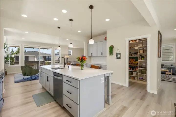 Alternative view of the kitchen highlighting the open layout, seamless flow into the dining area, durable flooring, and convenient walk-in pantry access. Alternative view of the kitchen highlighting the open layout, seamless flow into the dining area, durable flooring, and convenient walk-in pantry access.