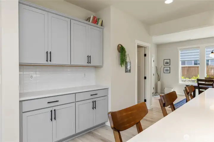 Functional built-in cabinetry area near the kitchen offers elegant shaker cabinets, a durable countertop surface, and extra storage for effortless organization. Functional built-in cabinetry area near the kitchen offers elegant shaker cabinets, a durable countertop surface, and extra storage for effortless organization.