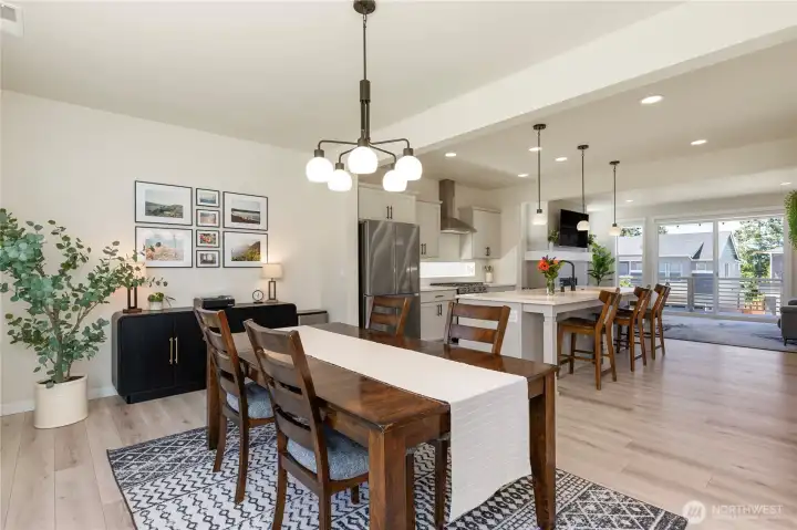 Expansive open-concept design connects the kitchen, dining, and living rooms, emphasizing a bright, airy floor plan with uniform wide-plank flooring throughout. Expansive open-concept design connects the kitchen, dining, and living rooms, emphasizing a bright, airy floor plan with uniform wide-plank flooring throughout.
