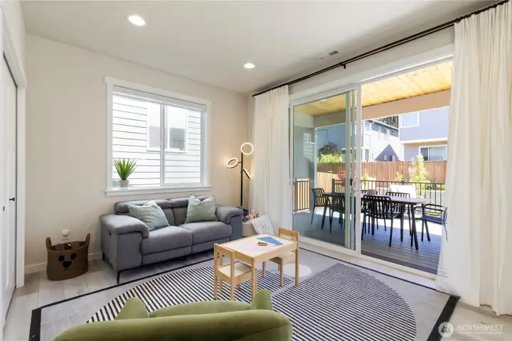 Versatile downstairs living area or family room features wide-plank flooring, a large sliding glass door, and flexible space for media or play. Versatile downstairs living area or family room features wide-plank flooring, a large sliding glass door, and flexible space for media or play.