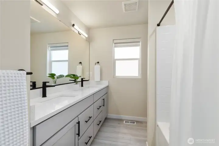 Secondary full bathroom includes a long vanity with modern solid surface countertops, premium fixtures, low-maintenance flooring, and a tub/shower combo. Secondary full bathroom includes a long vanity with modern solid surface countertops, premium fixtures, low-maintenance flooring, and a tub/shower combo.