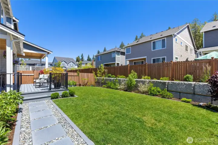 Rear exterior view emphasizes the custom 2024 mature front and back landscaping, fruit trees, blueberries, and structural retaining walls. Rear exterior view emphasizes the custom 2024 mature front and back landscaping, fruit trees, blueberries, and structural retaining walls.