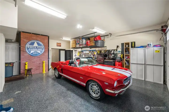 Two car garage with painted epoxy floors ; Hard wired for generator, Wired and have electrical outlets for a shop & Custom shelves
