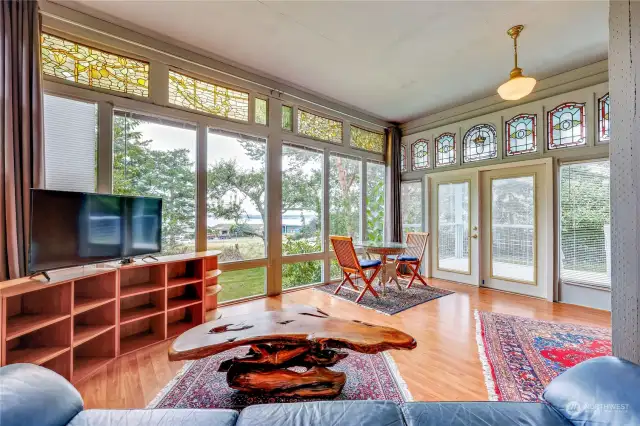 Notice the floor to ceiling windows and the French and German stained glass windows.  Deck just out the doors to the right.  View is across the meadow to Port Townsend Bay and Admiralty Inlet.