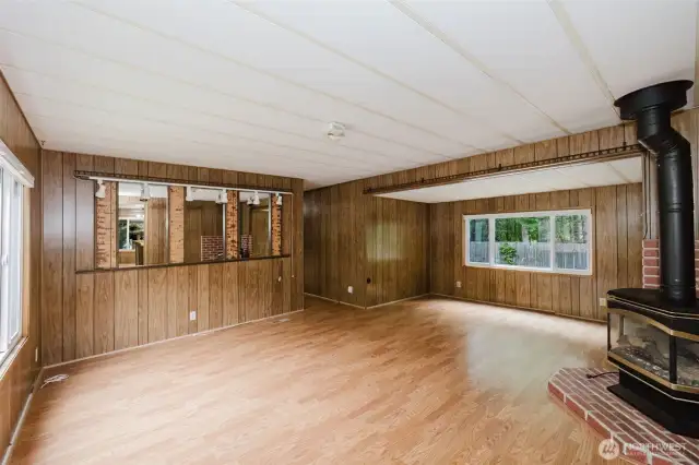 Spacious open living room with propane fireplace (not currently connected to propane), with front door to the left and the door to the hallway at the center.