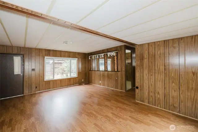 Living room showing the entry door and large double-pane vinyl picture window.  Door to the hallway is at center of photo.
