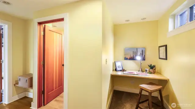 Landing at the bottom of the basement stairs with built in nook & 3/4 bath