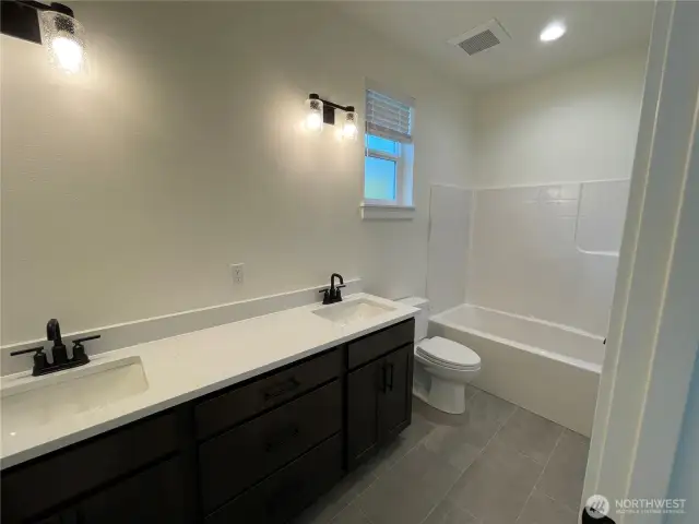Main bath with double sinks and shower/tub combo.