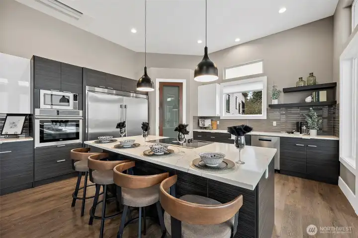 This modern kitchen features a large center island with seating, sleek cabinetry, and stainless appliances that create a stylish and highly functional cooking space. The open concept layout connects naturally to the surrounding living areas, making it ideal for entertaining and everyday living.