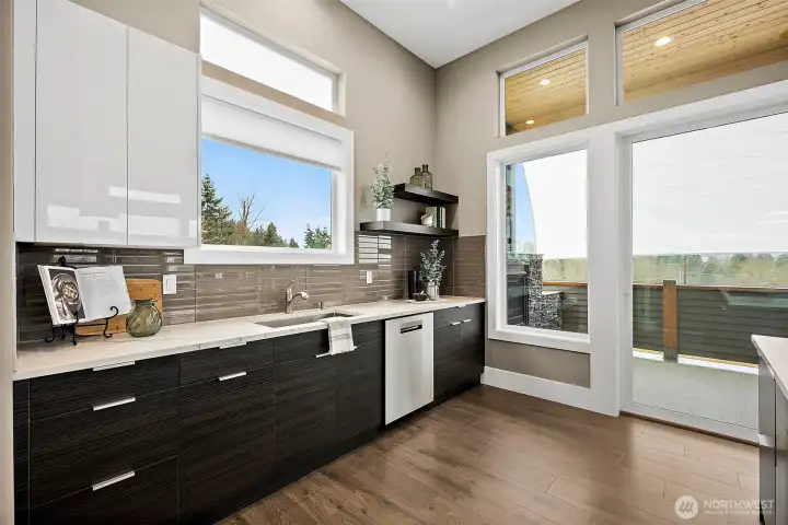 Modern kitchen in a home for sale in the River Rock community, featuring a large center island with seating, quartz countertops, stainless steel appliances, and sleek cabinetry. The open layout, abundant natural light, and connection to the living area create an ideal space for cooking, gathering, and everyday living.