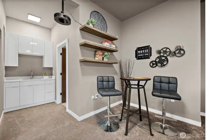 Spacious lower level entertainment room in this River Rock home in Auburn featuring a projector, large screen, wet bar, and comfortable seating areas. With direct patio access, this versatile rec room is designed for movie nights, hosting guests, and seamless indoor outdoor entertaining.