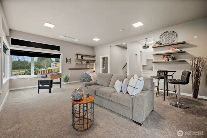 Spacious lower level entertainment room in this River Rock home in Auburn featuring a projector, large screen, wet bar, and comfortable seating areas. With direct patio access, this versatile rec room is designed for movie nights, hosting guests, and seamless indoor outdoor entertaining.