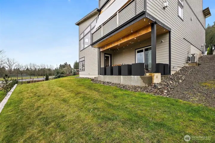 Private backyard with open lawn and views of the surrounding landscape, located behind this Auburn River Rock home. The outdoor space connects easily to the patio, offering room for gatherings, outdoor living, and enjoying the natural setting.