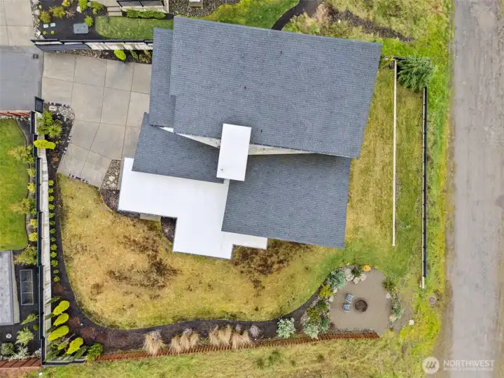 Modern exterior of a contemporary home for sale in the River Rock subdivision, featuring clean architectural lines, stone accents, a spacious driveway, and attached garage. Aerial and front views highlight its setting within the scenic River Rock community surrounded by natural greenery.