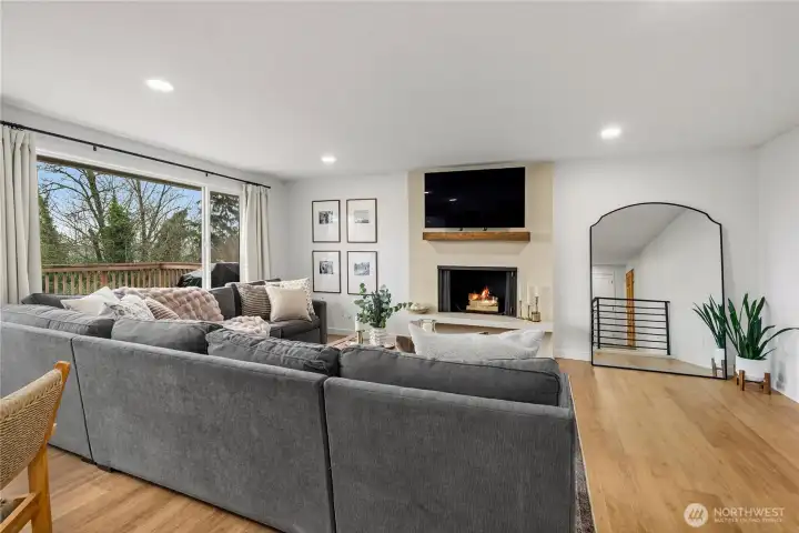 Updated living room with wide plank LVP flooring, beautiful sunset view and faux concrete floor to ceiling log fireplace.