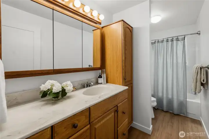 The full bath also got new wide plank LVP and fresh paint to set off the solid oak cabinetry.