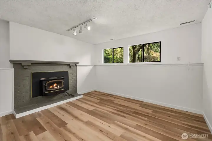 Second fireplace in basement with new plank flooring