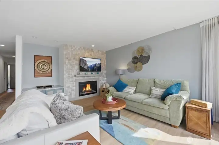 Waterfall tile feature wall surrounds electric gas fireplace.  Television hung with extension bracket for ease of viewing options.  Art and collection area for with cupboard to house your electronics and toys.  Updates in this room include flooring, canned lighting and updated wiring and plumbing for the remodel.  Sheer ceiling to floor curtains, electronic blinds and AC wall unit keep you comfortable all year around.  Full size couch and love seat pictured for size references.