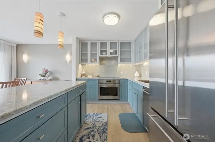 It took an engineer minded design  to satisfy a chef's wishes that have lovingly transformed this kitchen into a space any food lover would enjoy. We invite you to enjoy a gourmet smart kitchen with induction cook top, slim style overhead ventilation system and dove grey waved glass tile back splash. On the right a full size refrigerator with perfect size dishwasher sitting between it and the farm style single well deep sink. Soft closing deep drawers offer great lower cabinet storage  with even more storage hiding behind all these deep cabinets  Overhead soft closing, sheer cabinet faces and perfect under cabinet lighting for the final touch.