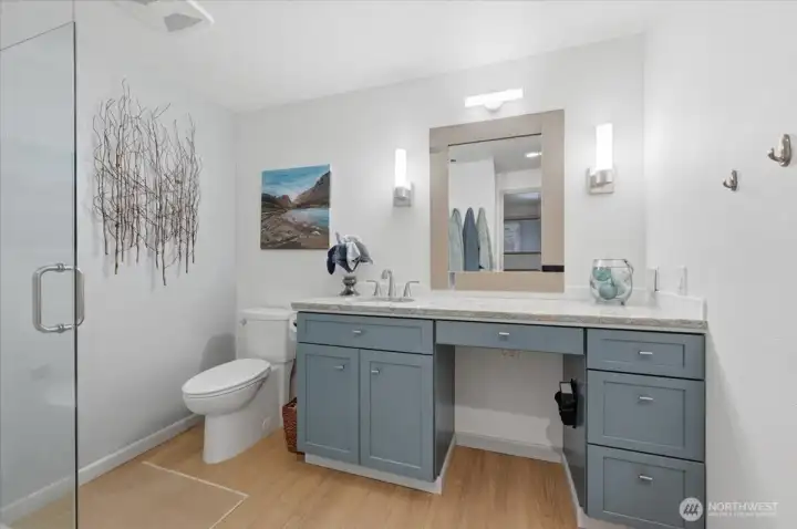 Custom glass shower surround and dresser size  vanity with make up chair space waterfall color counter top and deep drawer storage.  Low maintenance amenities for easing cleaning. Finally, Updated fixtures and lighting show the attention to detail in the en suite primary bath.
