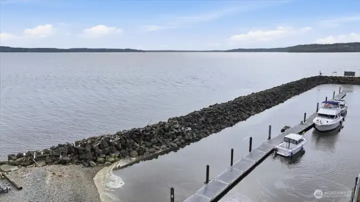Southwest View looking at Browns point and Maury Island and on a clear day you can see Tacoma City limits and Narrows bridge. Break water wall protects Des Moines Yacht club boat moorage and boat ramp. Des Moines Yacht club activity center not shown.