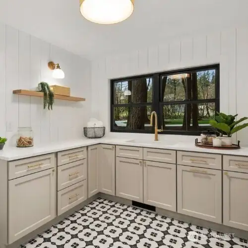 Beautifully designed laundry space with designer cabinetry and tile, shiplapped paneled walls, tons of counter space, laundry sink and views of the gorgeous yard!