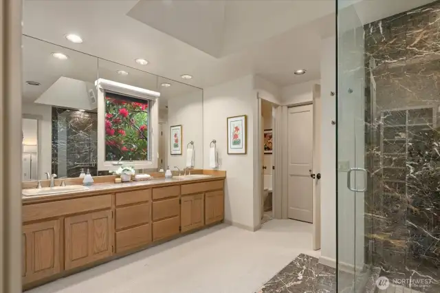 Spacious primary bathroom with walk in shower and lovely window outlook to the beautiful Rhododendron.