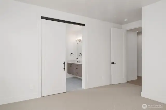 Contemporary barn door leads from Primary to the 5-pc bath