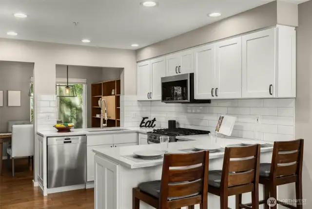 The kitchen features quartz countertops, premium appliances, & bar seating