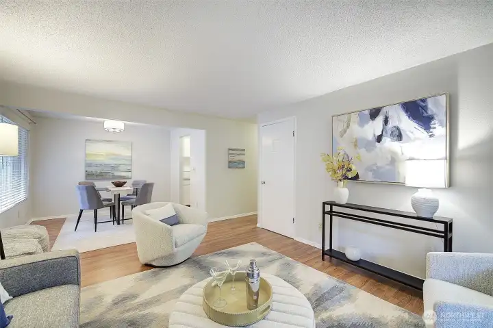 The living room flows directly into the large dining area with an oversized window and custom lighting.