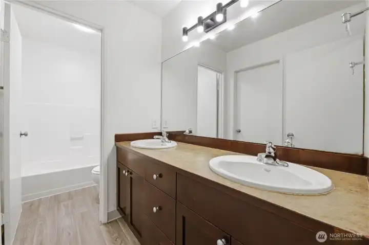 Upstairs bathroom features dual vanities, with doors to the hallway and