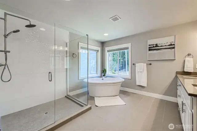 Spa-like primary bath with custom, oversized shower and designer stand-alone soaking tub.