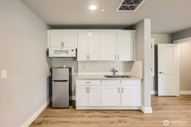 Kitchenette in lower living quarters. Stainless steel sink, microwave, refrigerator and DEEP walk-in storage space under the stairs would make a great pantry or closet.