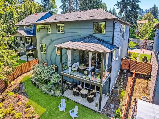 The back of this property is a wonderland! Chic outdoor spaces, grass to play on, garden space, mature landscaping everywhere you look, a wall of gorgeous vine-wrapped trees, river rock and more!