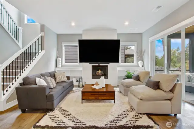 Elegant, modern and full of sunlight - Family room with dramatic windows, electric fireplace and covered verands overlooking a wall of forest trees.