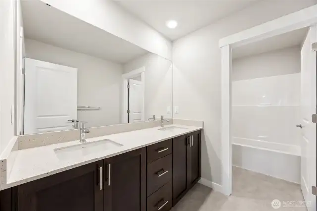 Hall bathroom with double vanity and separate door to tub/shower and toilet for convenience. Actual home is under construction and finishes, materials, and colors will vary. See site agent for details.