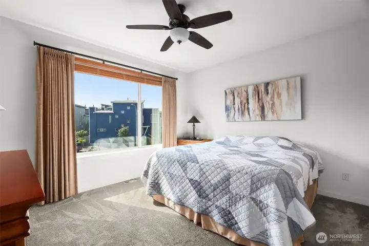 Primary suite on main level has plenty of space for large furnishings, ceiling fan and large window to the front of the house