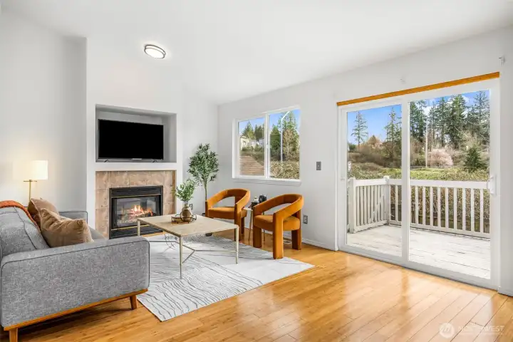 The living room features a gas fireplace and a sliding glass door opening directly to the deck with peaceful backyard views.
