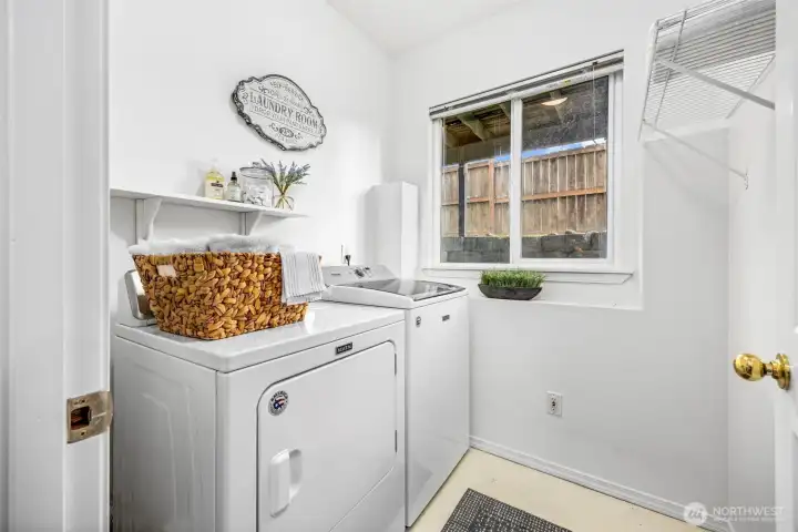 The laundry room includes a full-size washer and dryer with added shelving for storage.