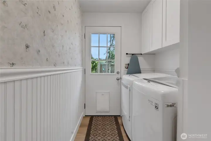 Utility room with newly added upper cabinets, wainscoting and a single patio door leading to the backyard with a built-in dog door for your furry friend!