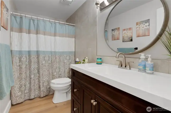 Updated bathroom with tiled surround, decorative mirror, newer toilet and a generously sized vanity!