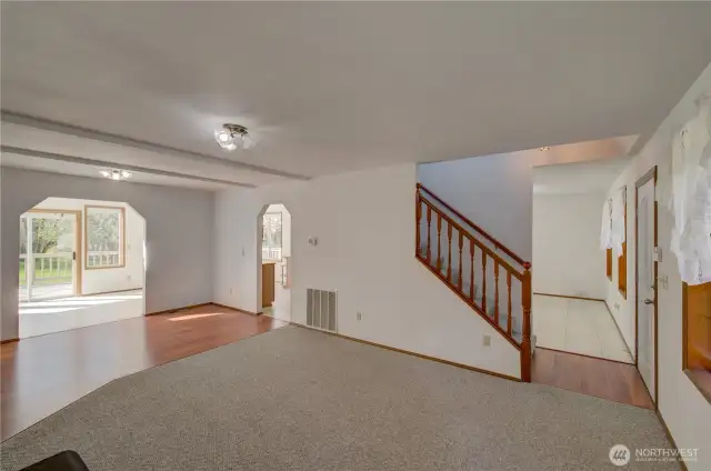 Looking through the living room towards the dining room, stairs to the upper bedrooms, kitchen and sun room.