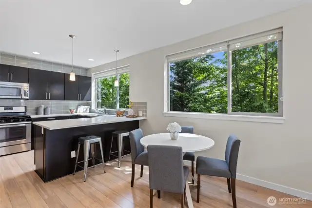 Dining area and a seating area at the kitchen counter with lots of overhead lighting, windows and a beautiful wood floor.