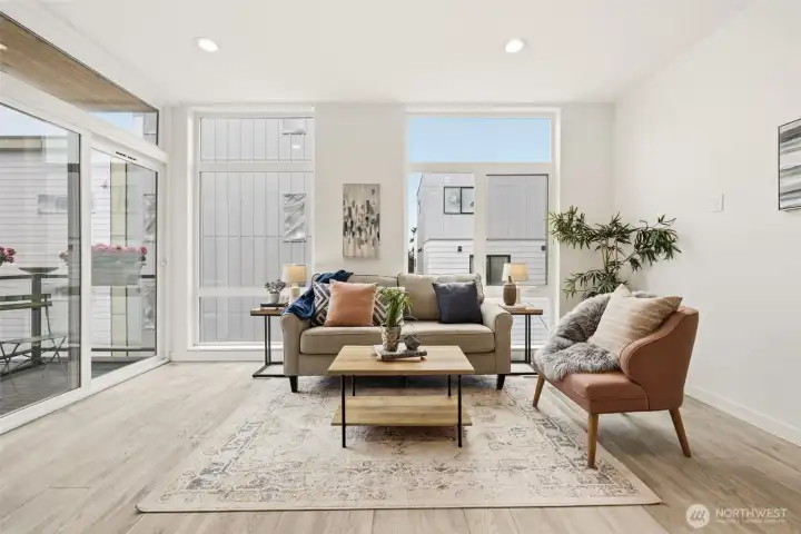 Floor-to-ceiling windows in the air conditioned living room and dining room lavish the space in light. To the left is the deck with convenient access from the kitchen.