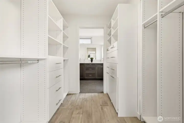 Spacious custom closet in the primary suite, leading to the primary bath with heated tile floors.