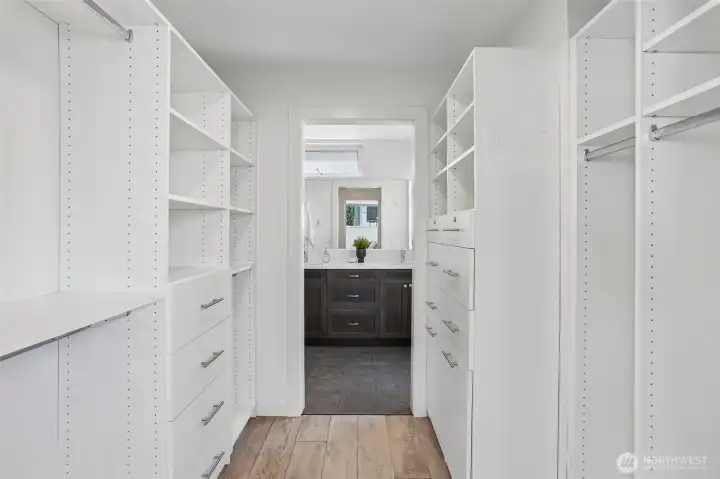 Spacious custom closet in the primary suite, leading to the primary bath with heated tile floors.